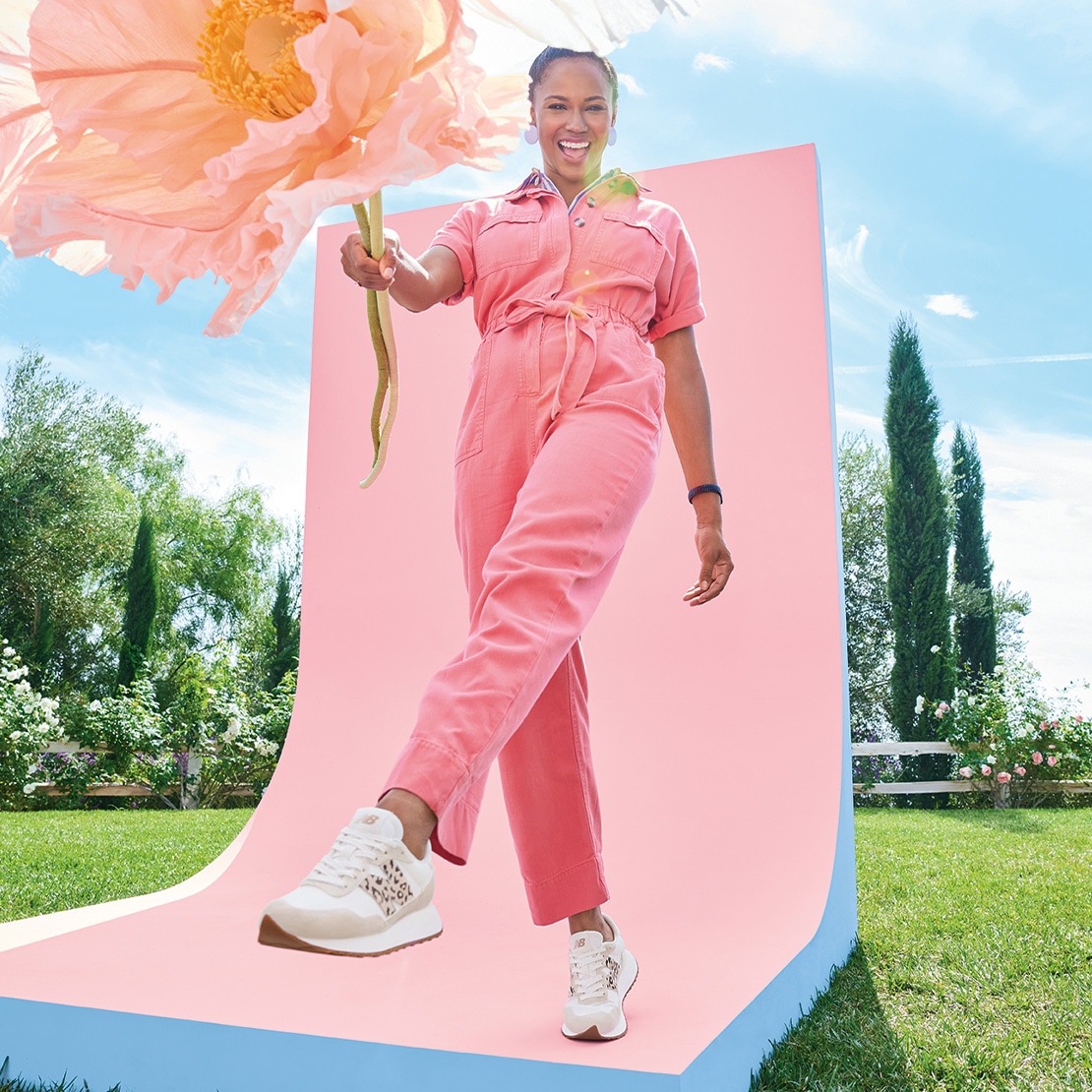 woman in pink jumpsuit holding a giant puffy flower