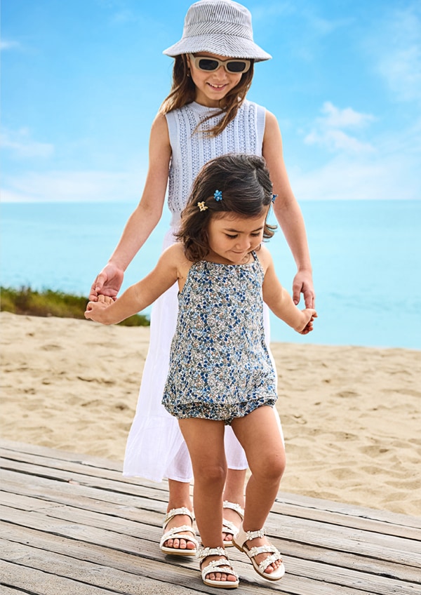 younger and older girl walking on the beach wearing matching blowfish sandals