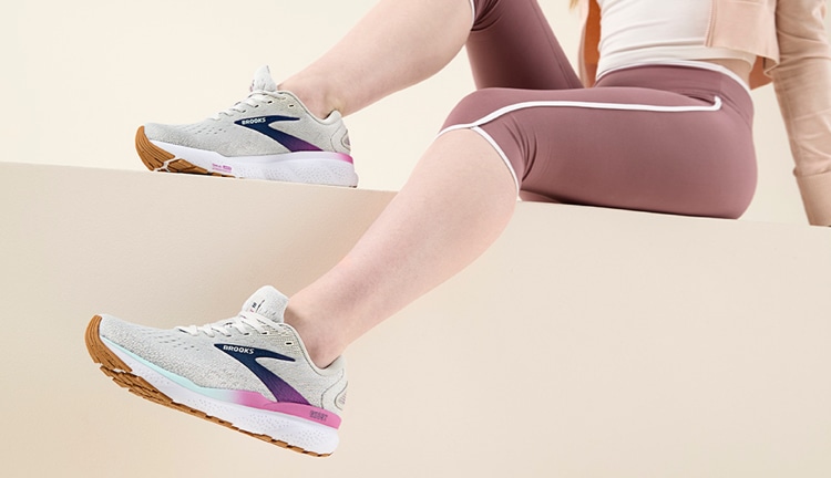 legs of woman leaning back wearing brooks shoes and brooks shoes lying on ground