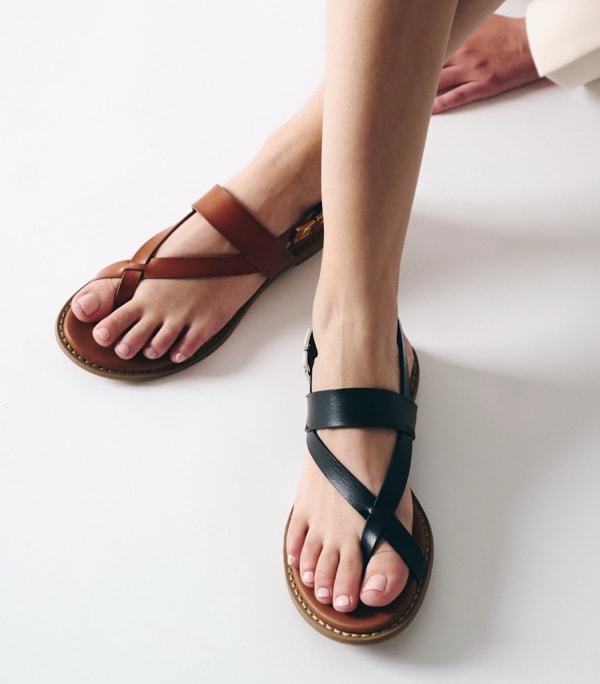 legs of woman stting down wearing black and brown franco sarto sandals