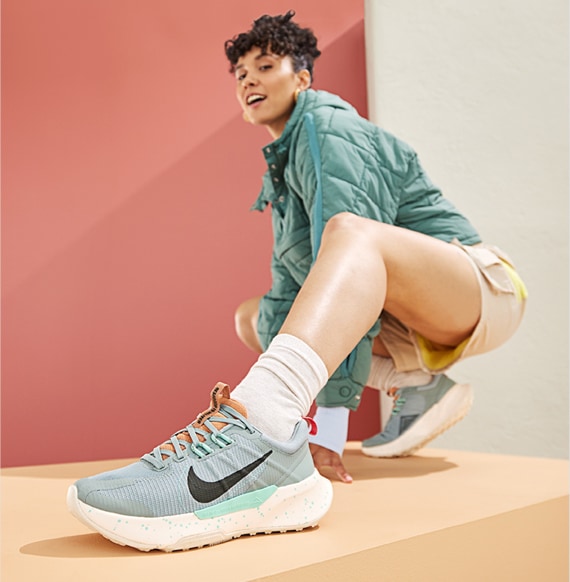 woman in green jacker wearing and gray and mint nike performance sneakers