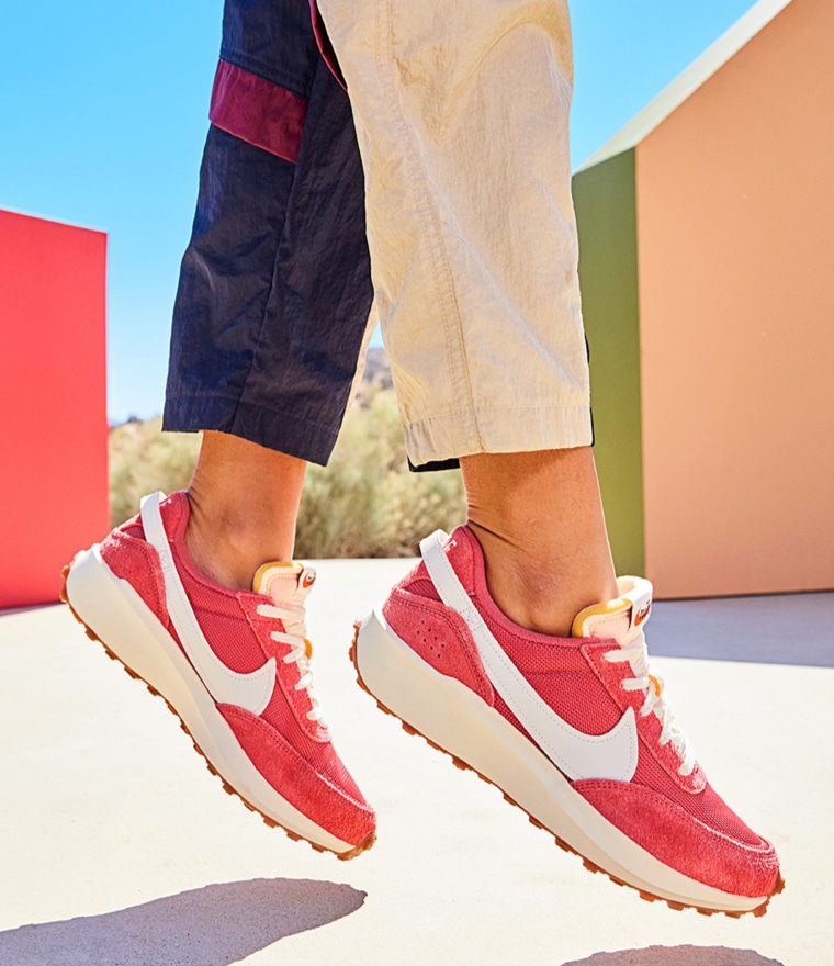feet of person jumping wearing red nike waffle sneakers