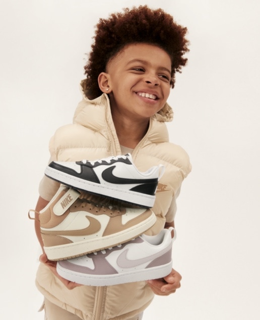 Kid holding three Nike shoes