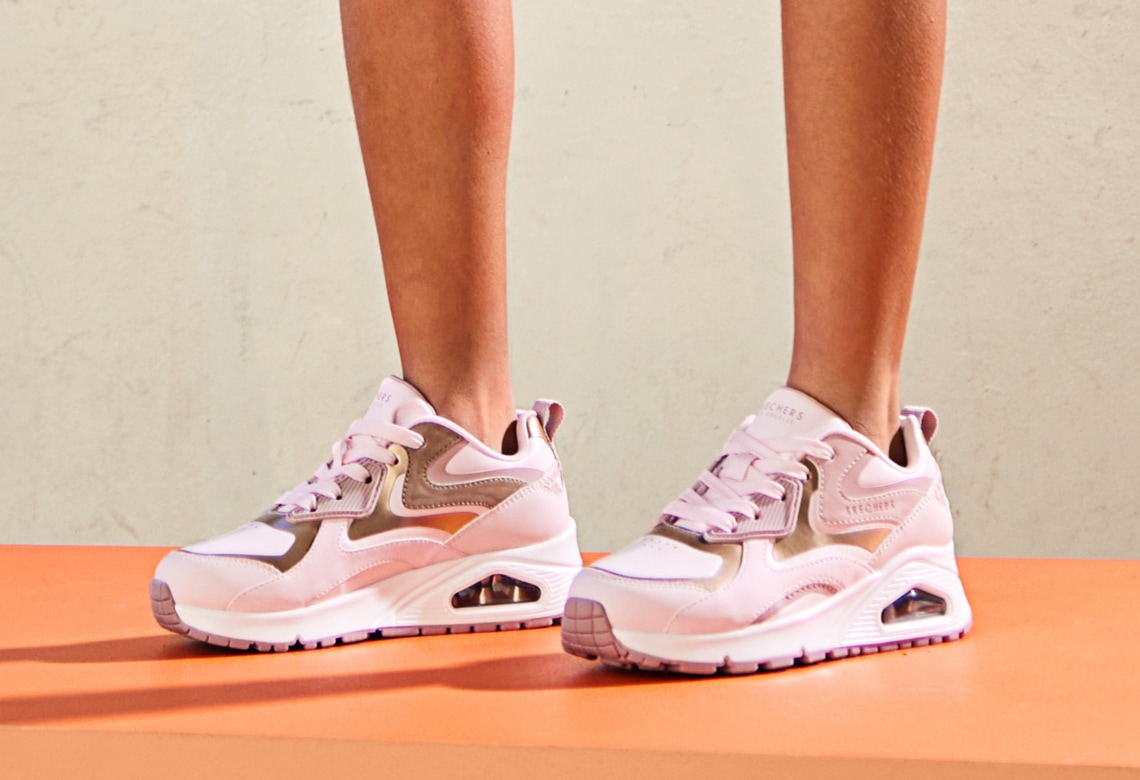 feet of woman wearing pink and white skechers uno