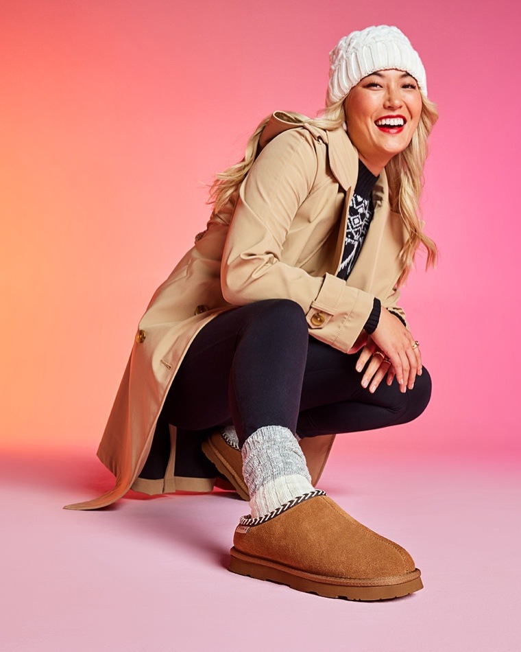 woman in hat wearing brown bearpaw shorty slips ons
