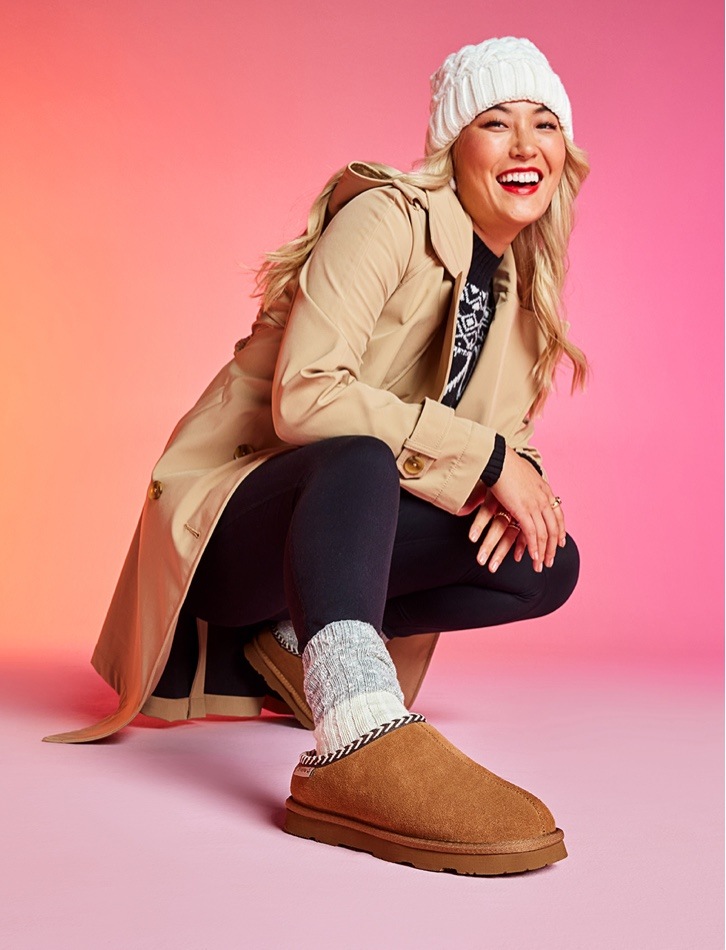 woman in hat wearing brown bearpaw shorty slips ons