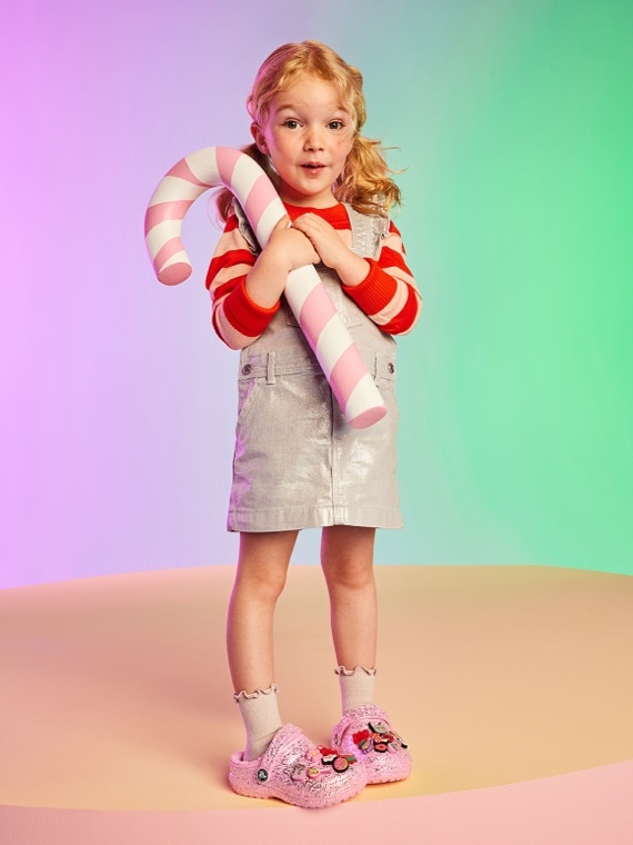 toddler holding a candy cane wearing pink crocs with jibbitz