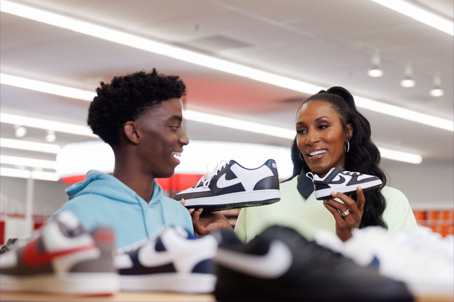 Lisa Leslie and son holding black and white Nike sneakers in store