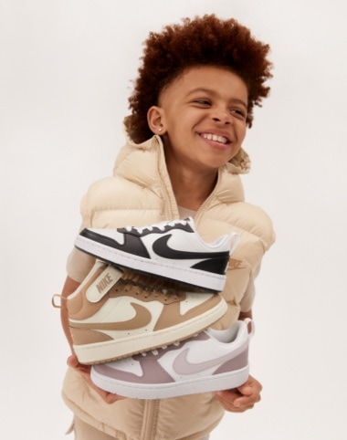 boy holding three Nike sneakers