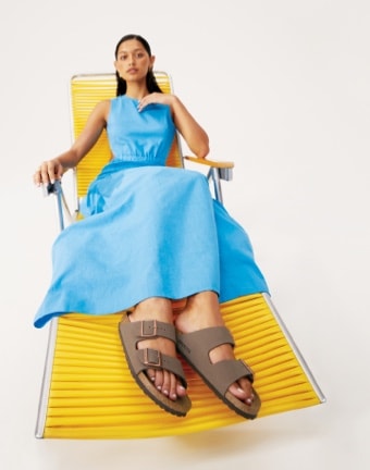 woman sitting on yellow chair wearing Birkenstock Arizona footbed sandals