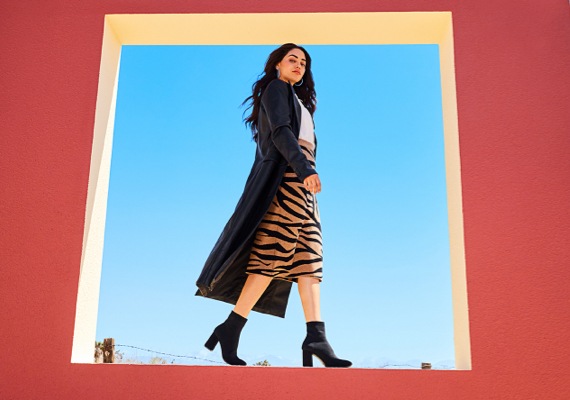 woman in tiger print skirt and black coat wearing black heels boots