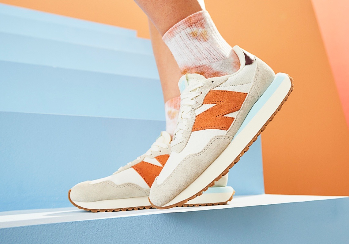 feet of person wearing cream, gray, orange and light blue new blance 237 sneakers
