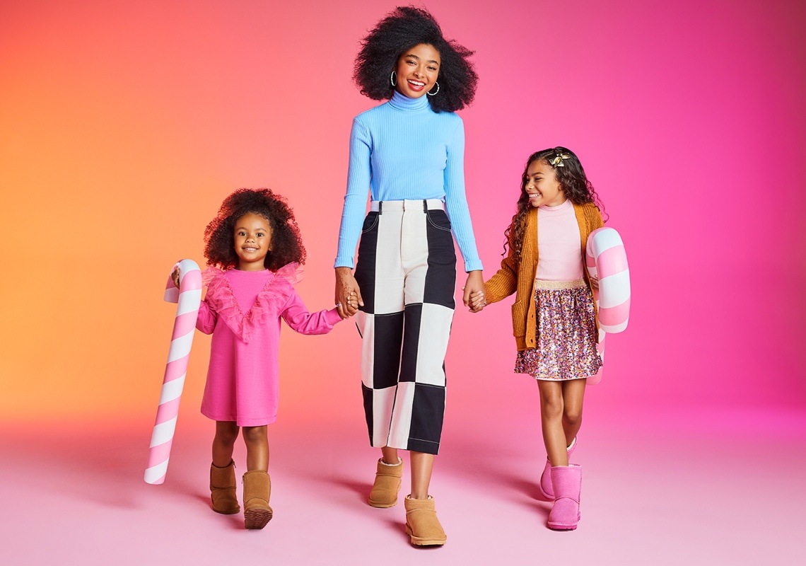 mom and two daughters wearing cozy boots holding christmas decor
