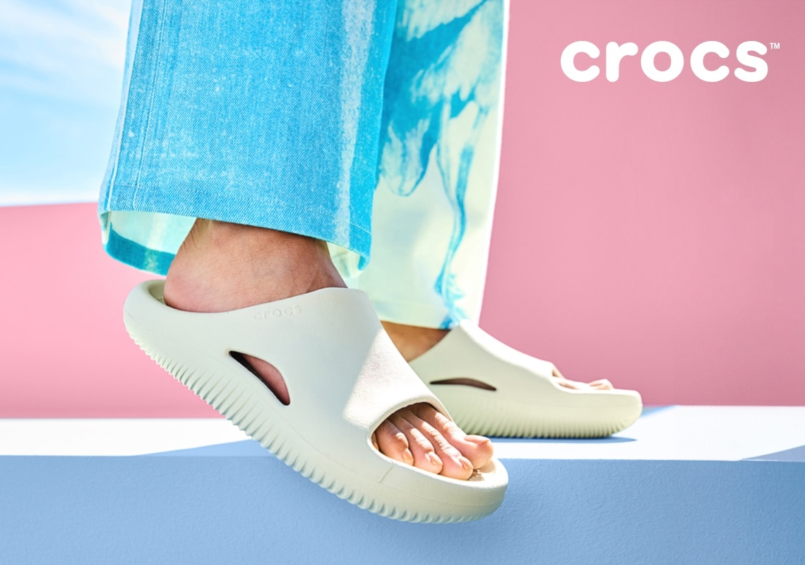 feet of woman in blue pants wearing crocs slides