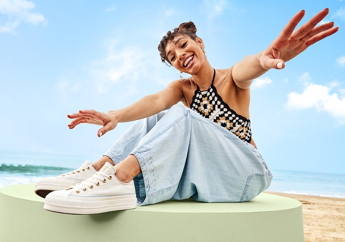woman in festival wear with arms open wearing high top sneakers