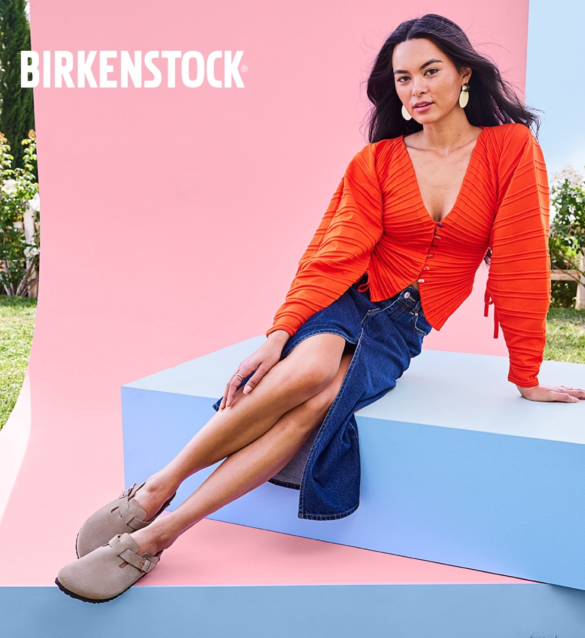 woman in jean skirt sitting down wearing birkenstock boston clogs