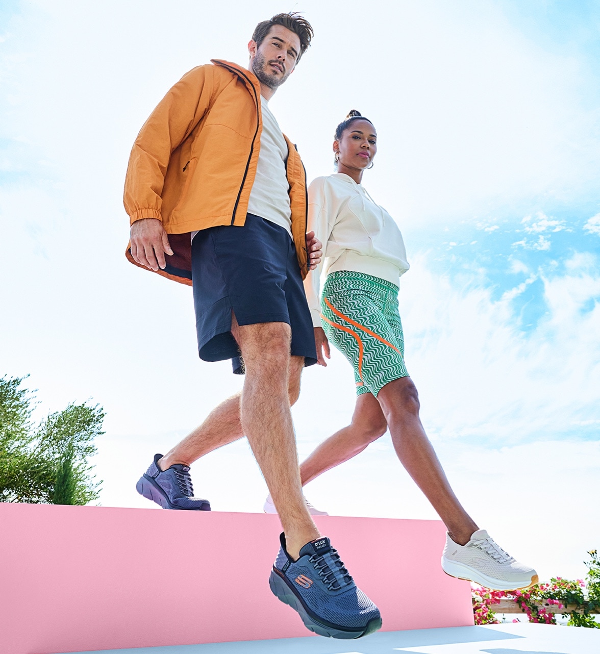 man and woman in activewear walking down the steps wearing skechers
