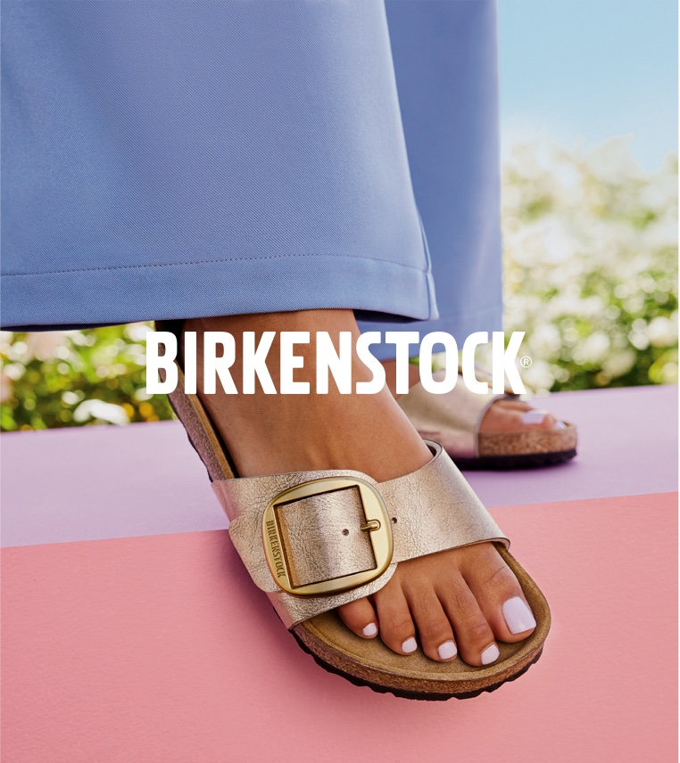 feet of woman wearing gold birkenstock sandals with big buckle