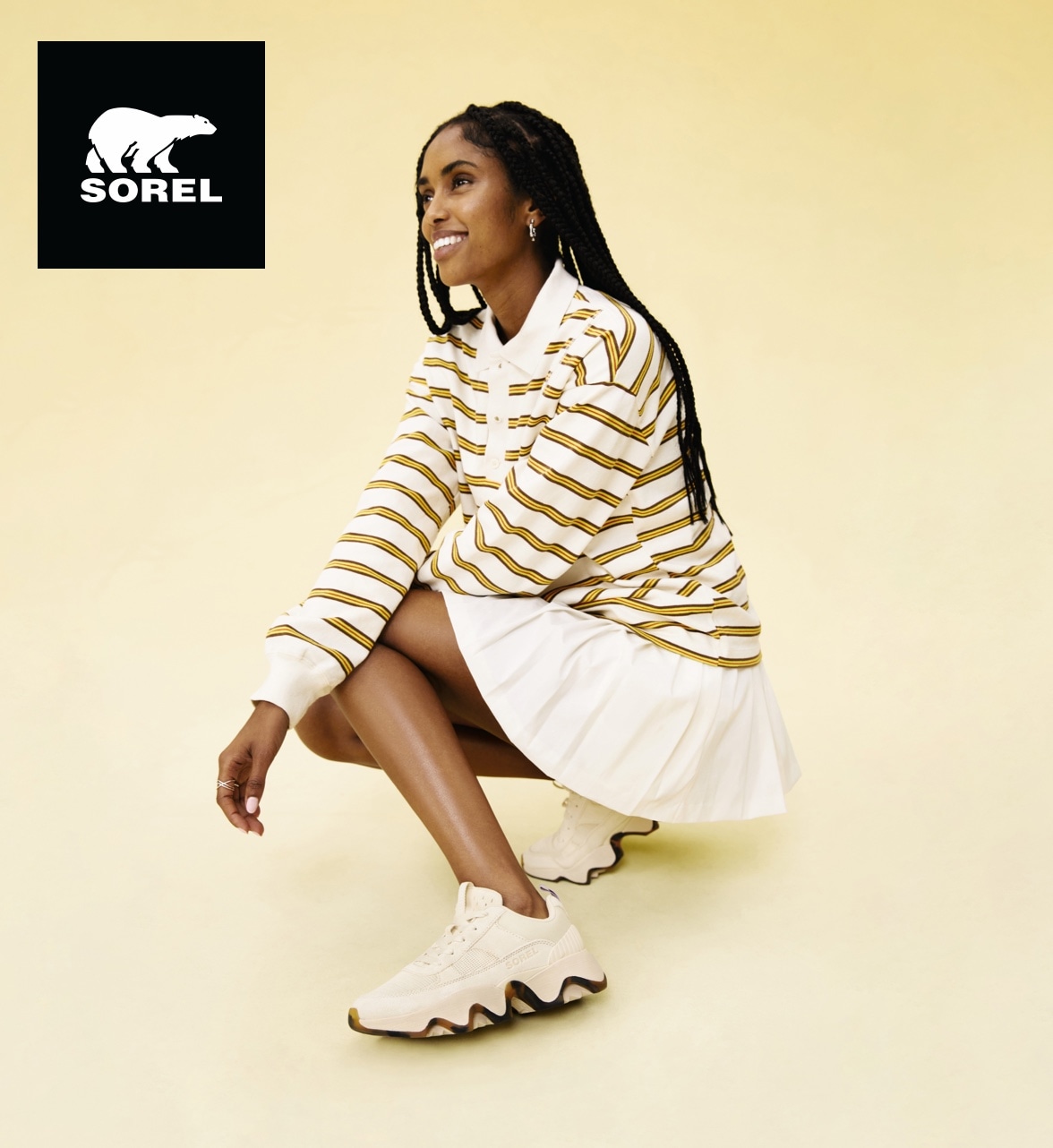 woman squatting down wearing sorel tennis shoes with sorel logo
