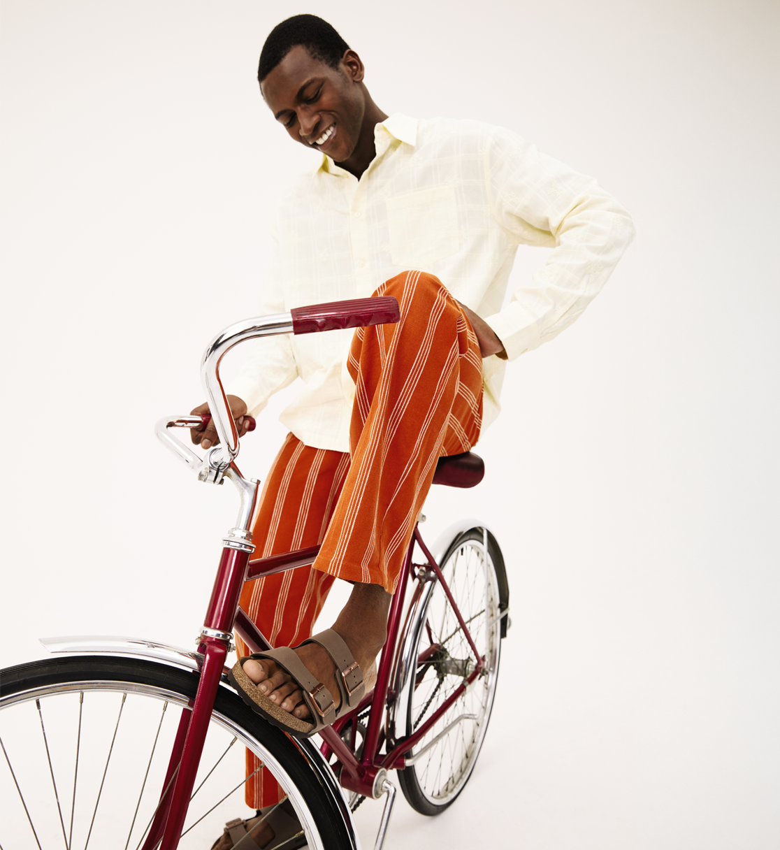 man in orange striped pants sitting on bike wearing sandals