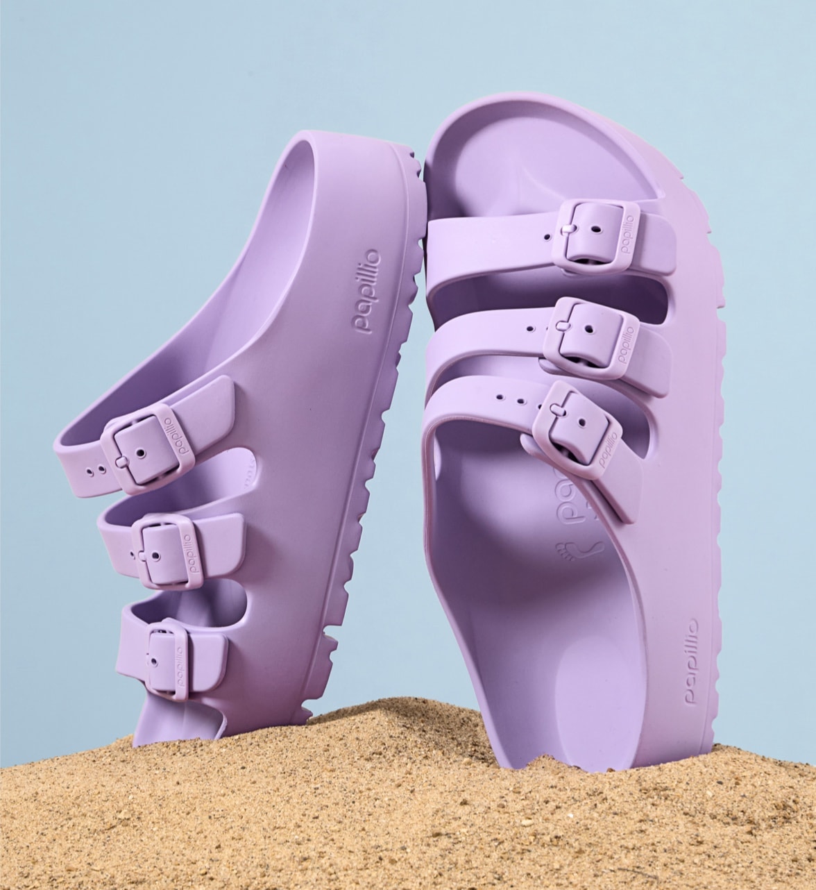 purple birkenstock platform sandals standing in sand