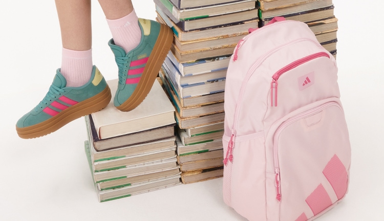 Girl wearing turquois adidas shoes standing on school books