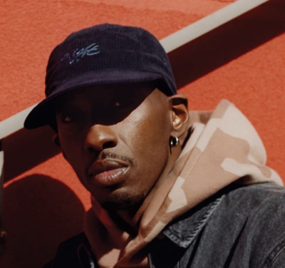 face of man wearing a hat and camo hoodie