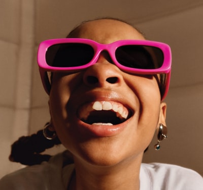 young girl with pink sunglasses smiling