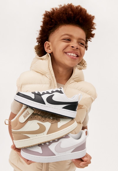 young boy holding nike court sneakers