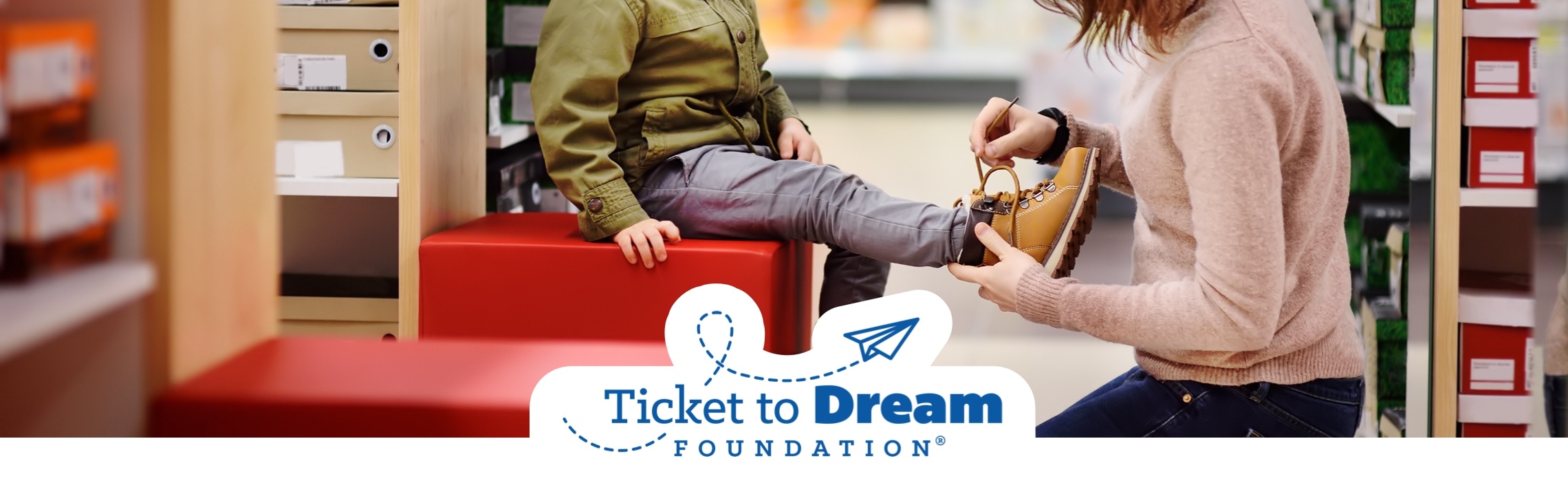 woman putting shoe on child in famous footwear store with ticket to dream foundation logo