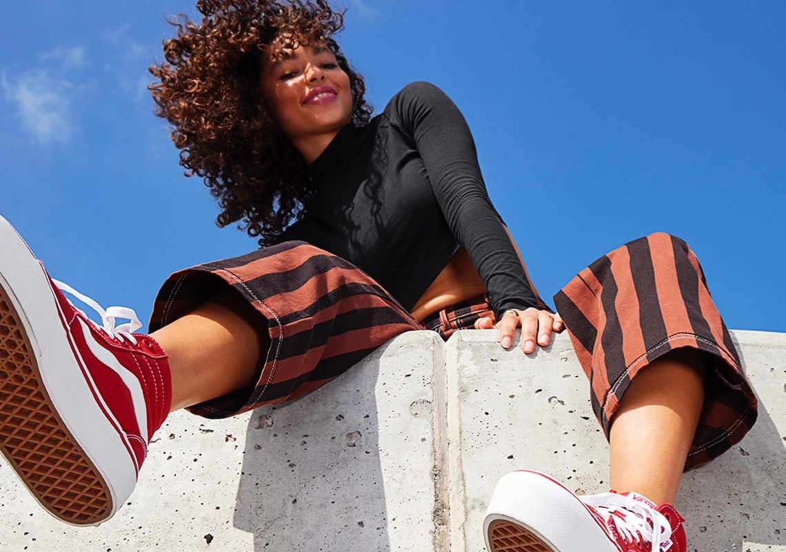 woman sitting on a wall wearing high tops red vans